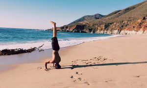 Image of a guy on a beach doing a handstand to illustrate the power of looking at things from a different perspective