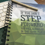 Image of notebook with an inspirational message on the cover on a desk