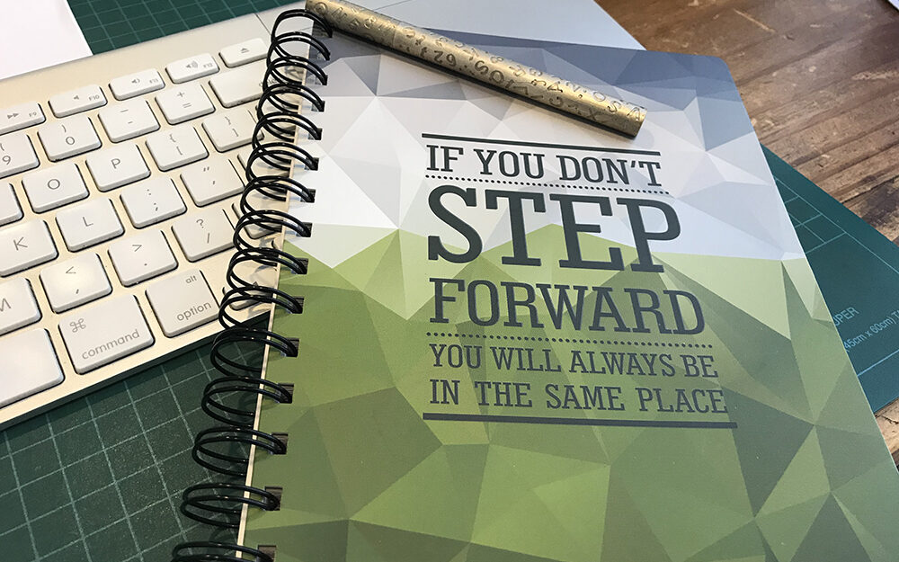 Image of notebook with an inspirational message on the cover on a desk